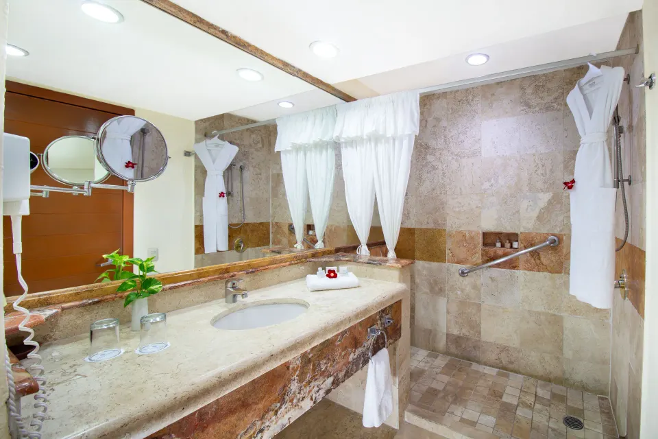 One Bedroom Suite bathroom vanity and shower at Plaza Pelicanos Grand Beach Resort.
