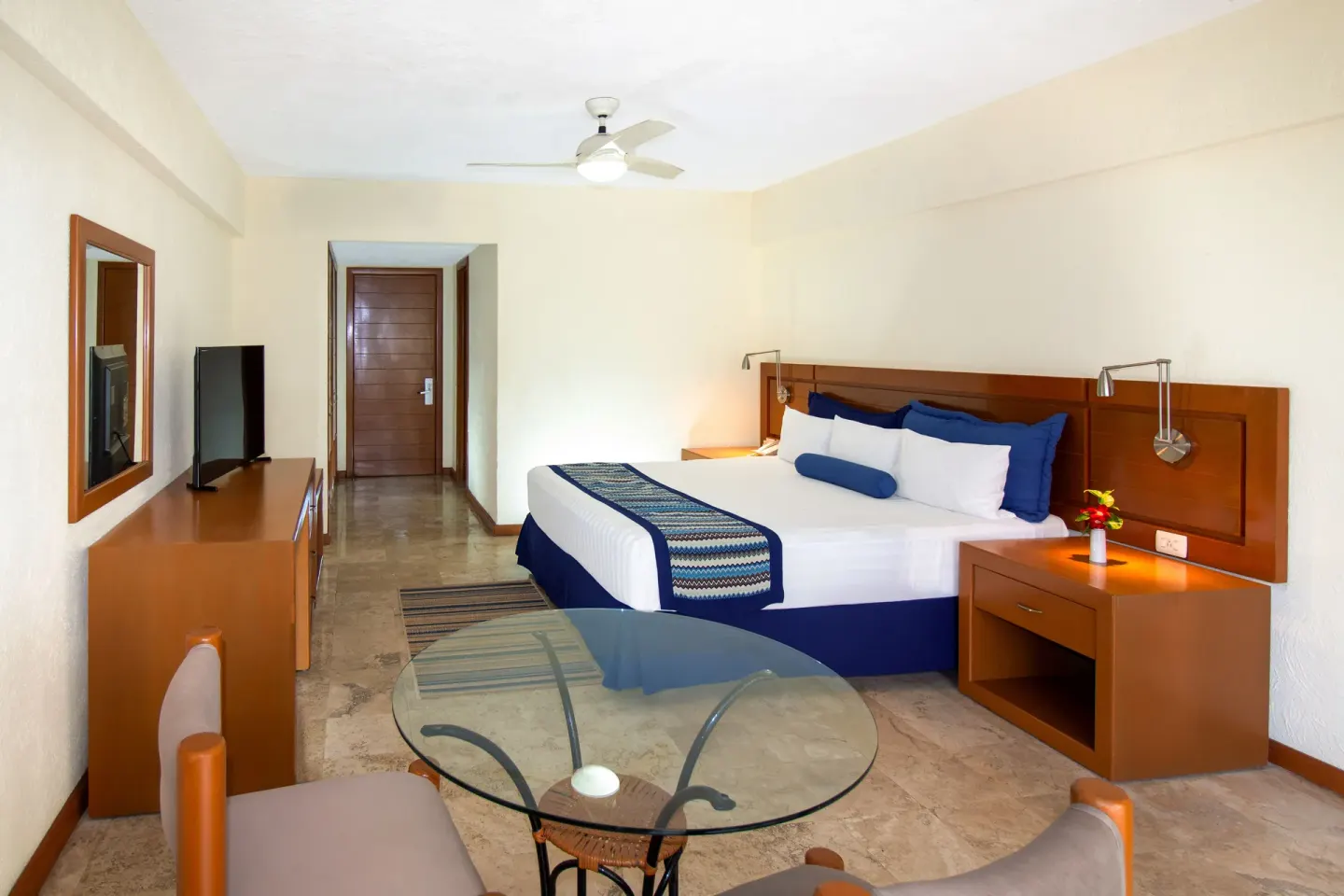One Bedroom Suite king bed and glass table at Plaza Pelicanos Grand Beach Resort.