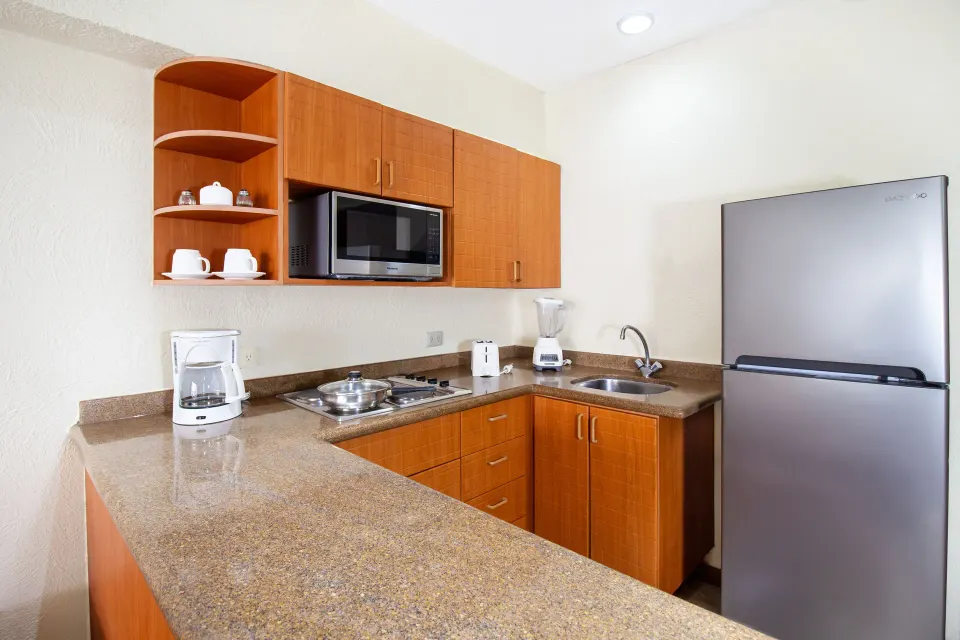 One Bedroom Suite kitchenette with refrigerator at Plaza Pelicanos Grand Beach Resort.