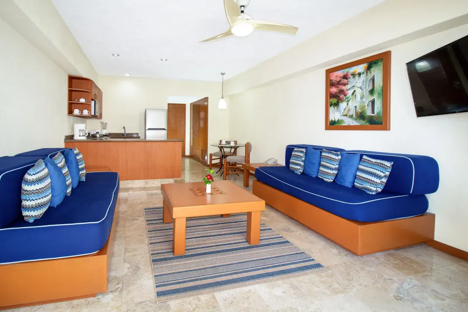 One Bedroom Suite living area with blue sofas at Plaza Pelicanos Grand Beach Resort.