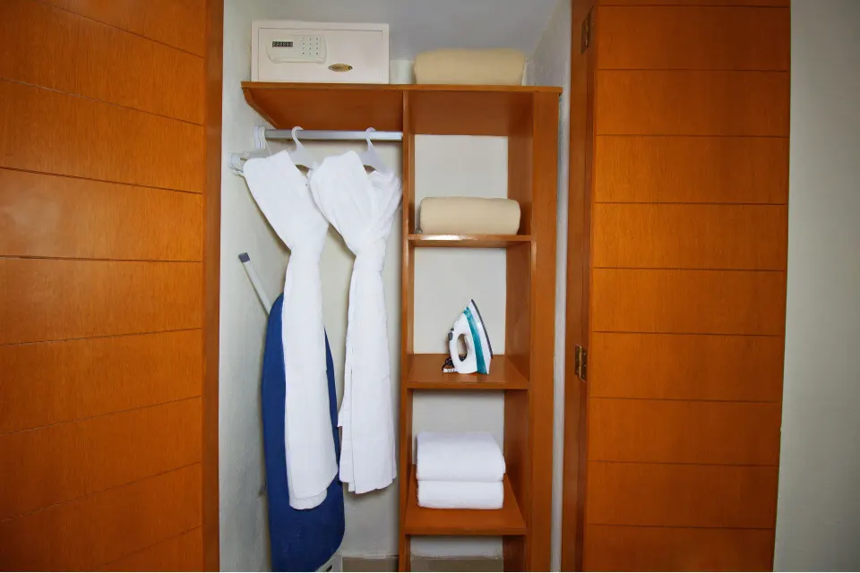 Standard Room closet with robes, safe, iron, and linens at Plaza Pelicanos Grand Beach Resort.
