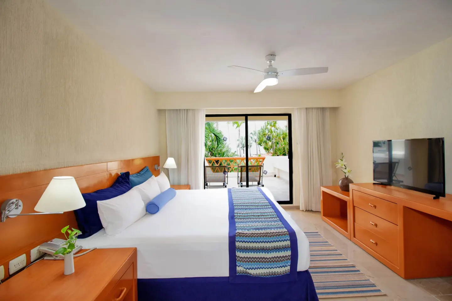 Standard Room king bed with balcony doors at Plaza Pelicanos Grand Beach Resort.