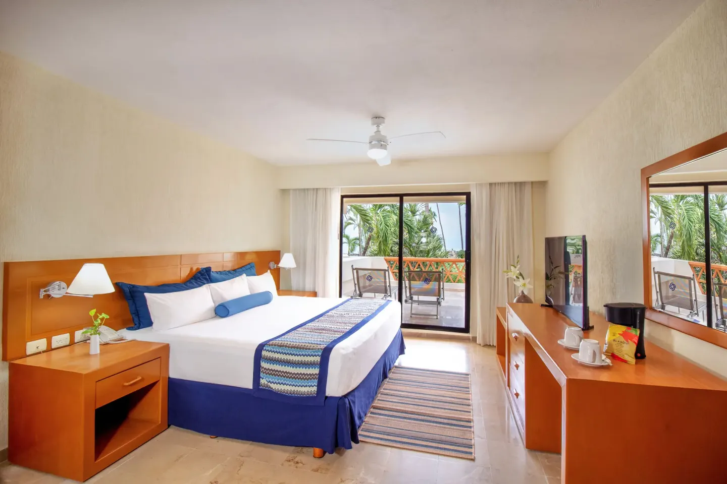 Standard Room king bed with dresser and balcony at Plaza Pelicanos Grand Beach Resort.