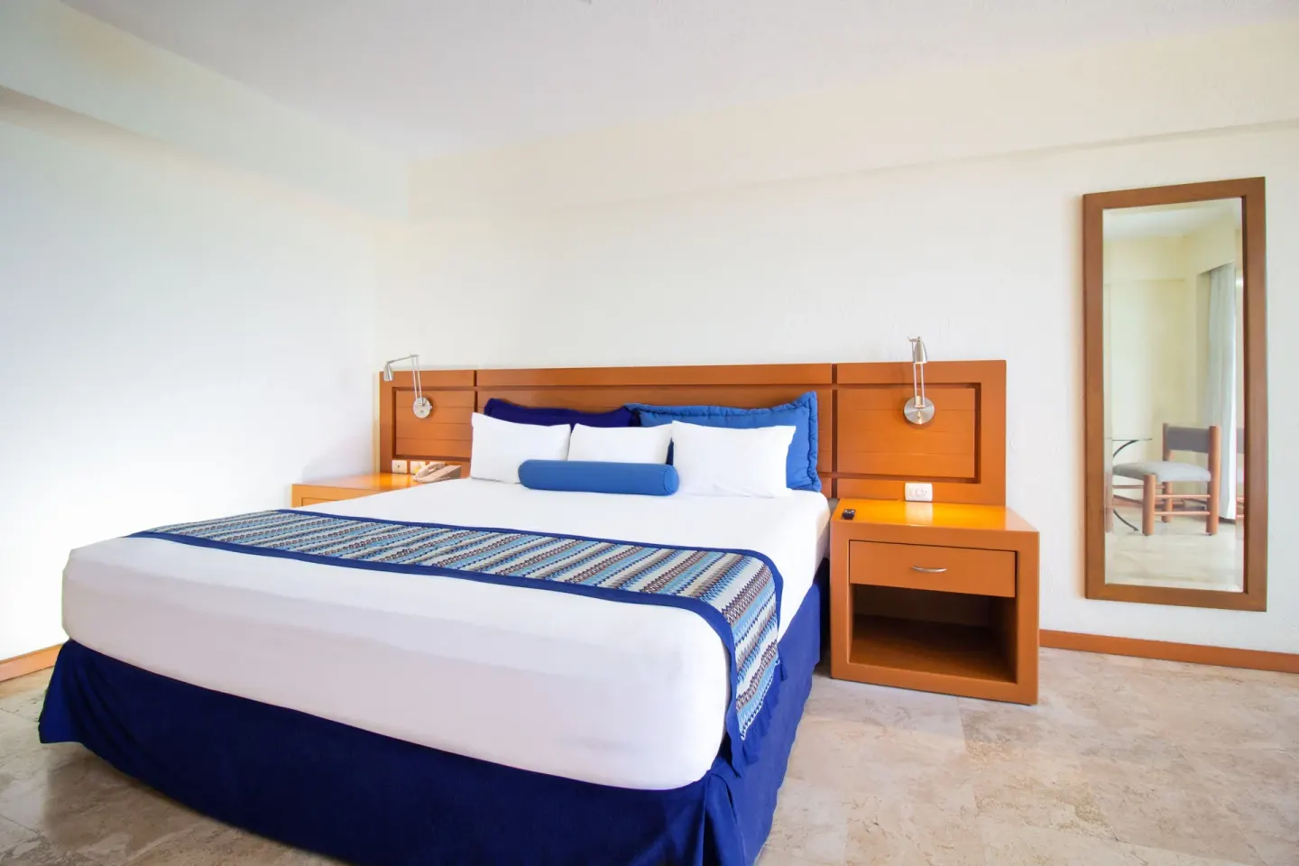 Standard Room with one large bed and wall mirror at Plaza Pelicanos Grand Beach Resort.