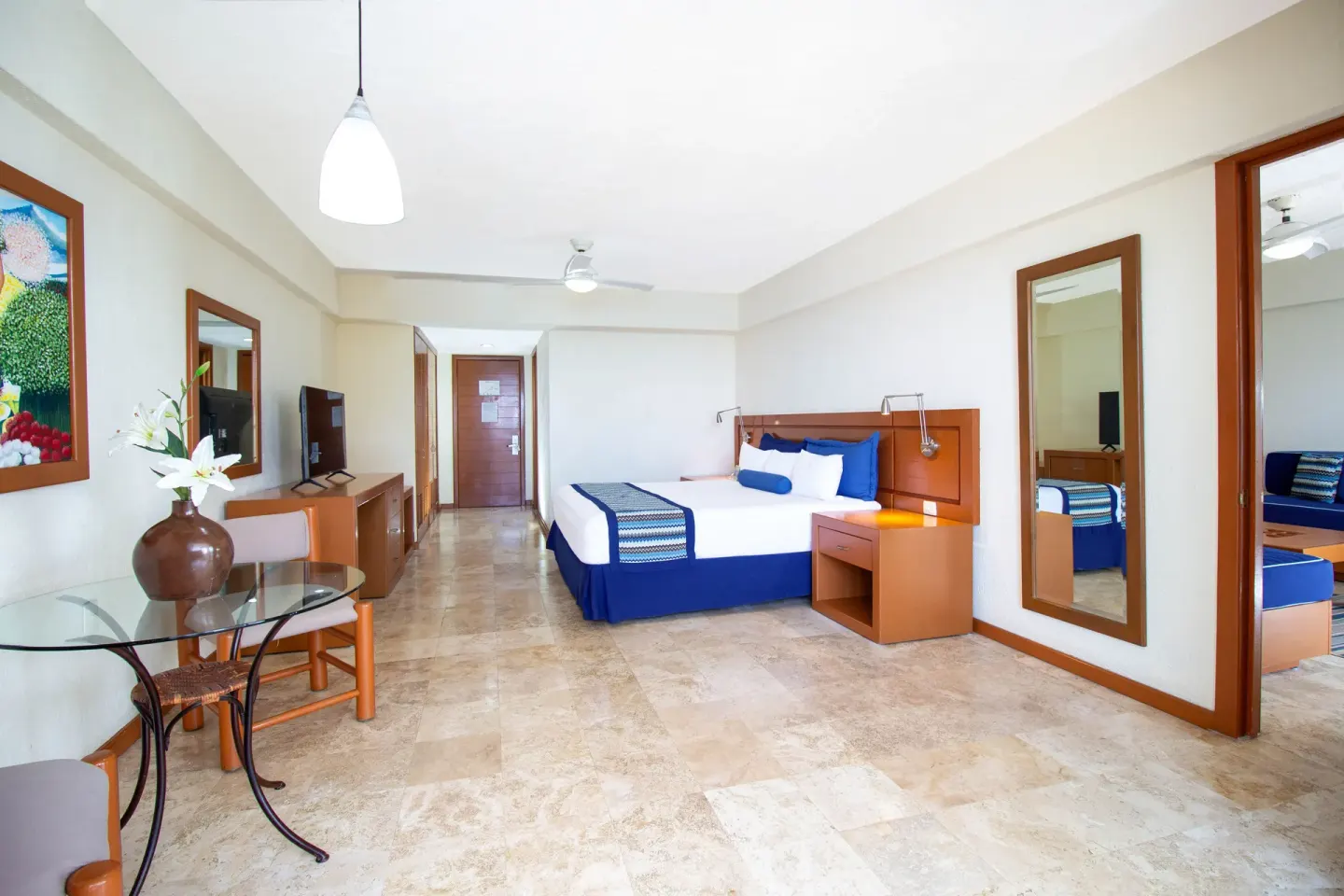 Standard Room with one bed, dining table, and mirrors at Plaza Pelicanos Grand Beach Resort.