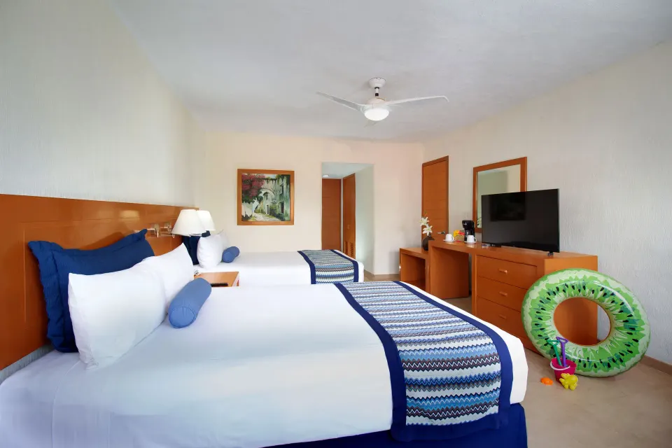 Standard Room with two beds, TV, and pool float at Plaza Pelicanos Grand Beach Resort.