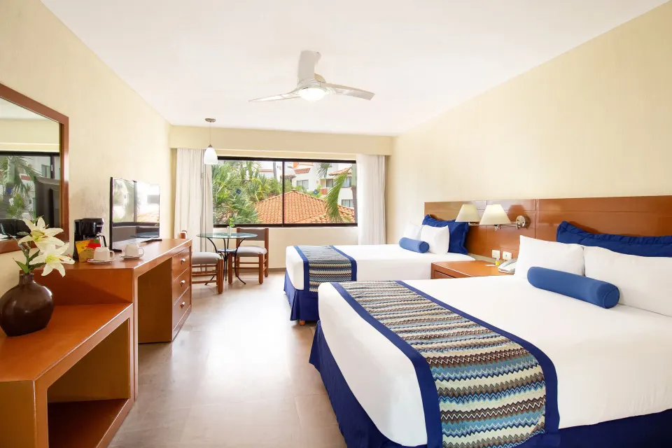 Standard Room with two beds, dresser, and window at Plaza Pelicanos Grand Beach Resort.