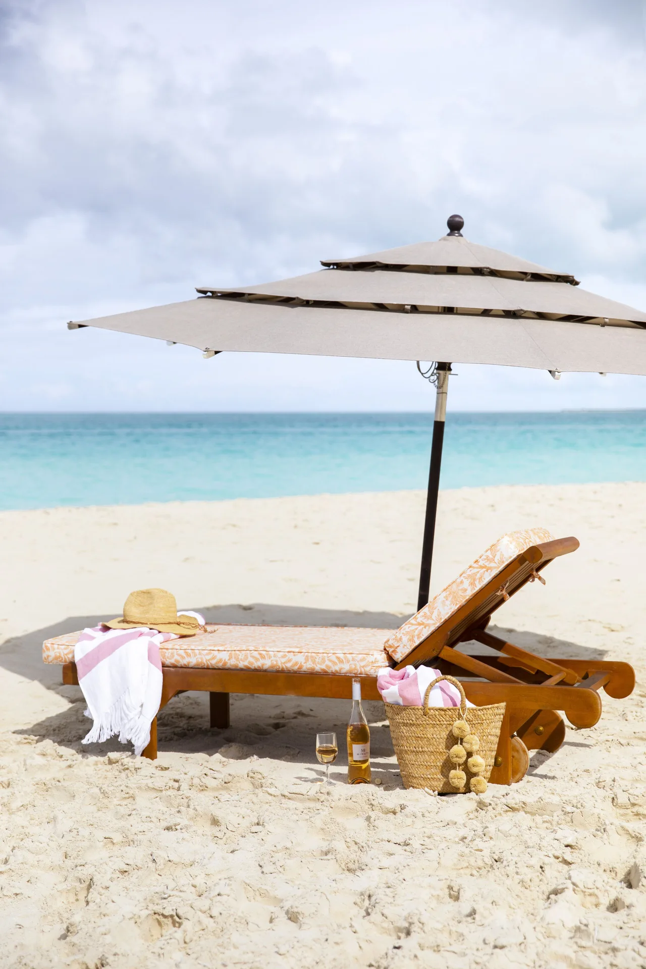Beach loungers and umbrella on pale sand by the sea at Point Grace.