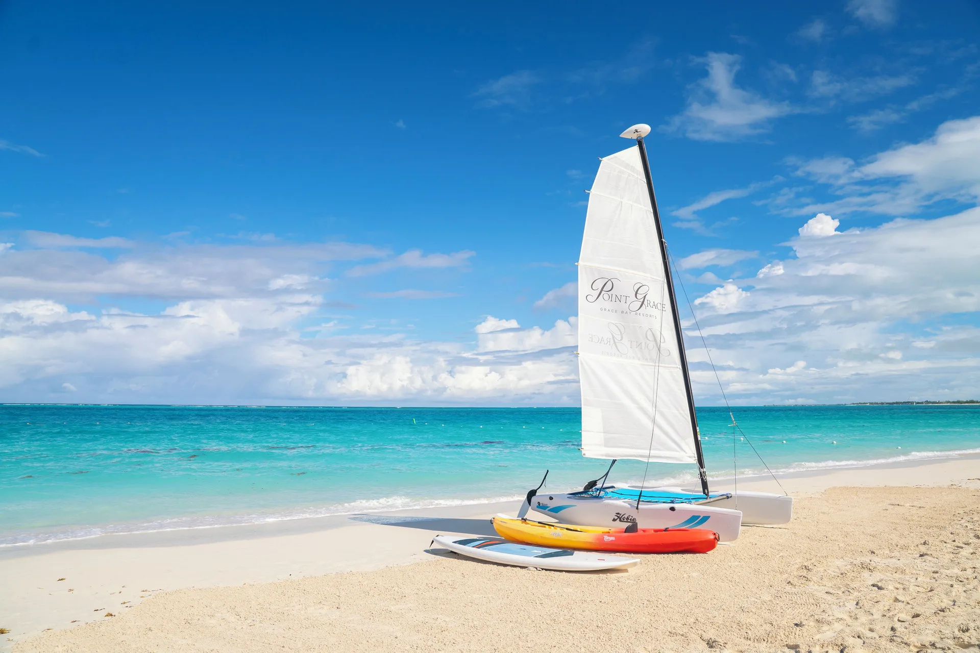 Small sailboat on the sandy beach with turquoise water at Point Grace.