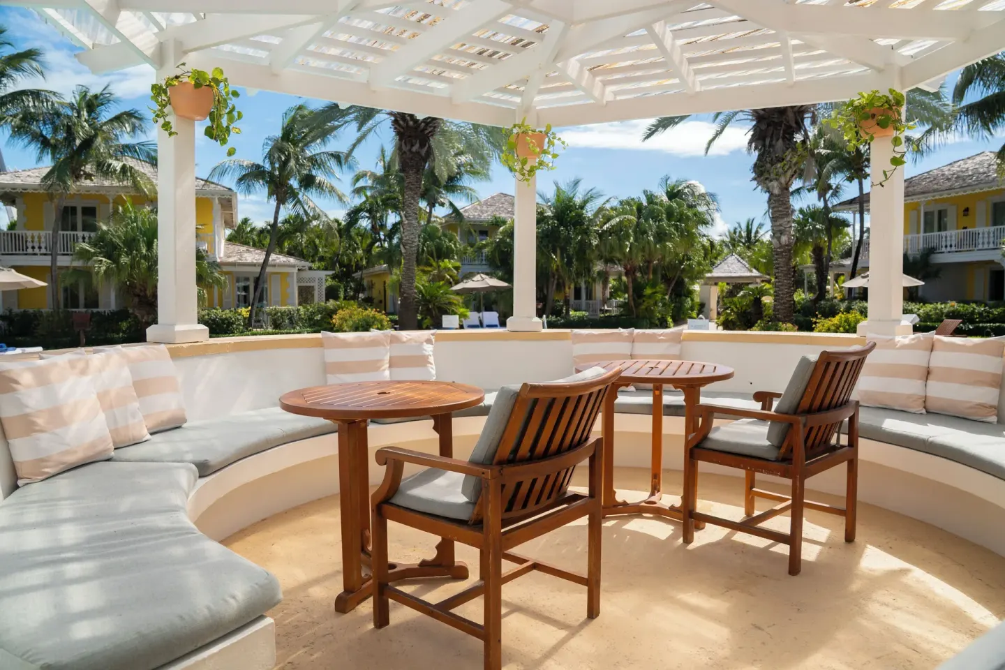 Covered garden lounge with round tables and cushioned seating at Point Grace.