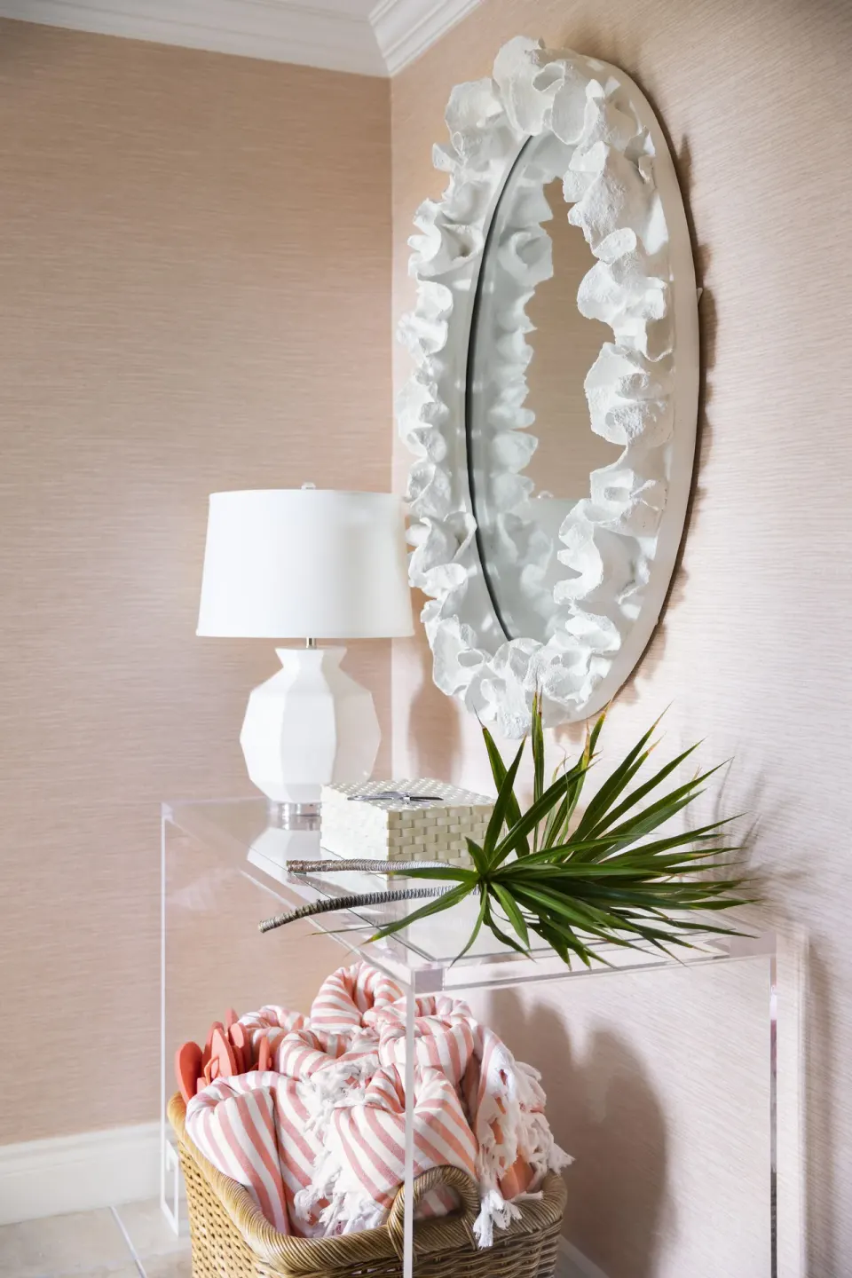 Entry console with shell-framed mirror, lamp, towels, and palm frond at Point Grace.