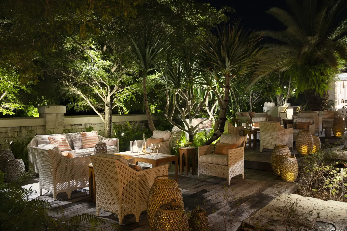 Nighttime garden lounge with wicker seating and lanterns at Point Grace.