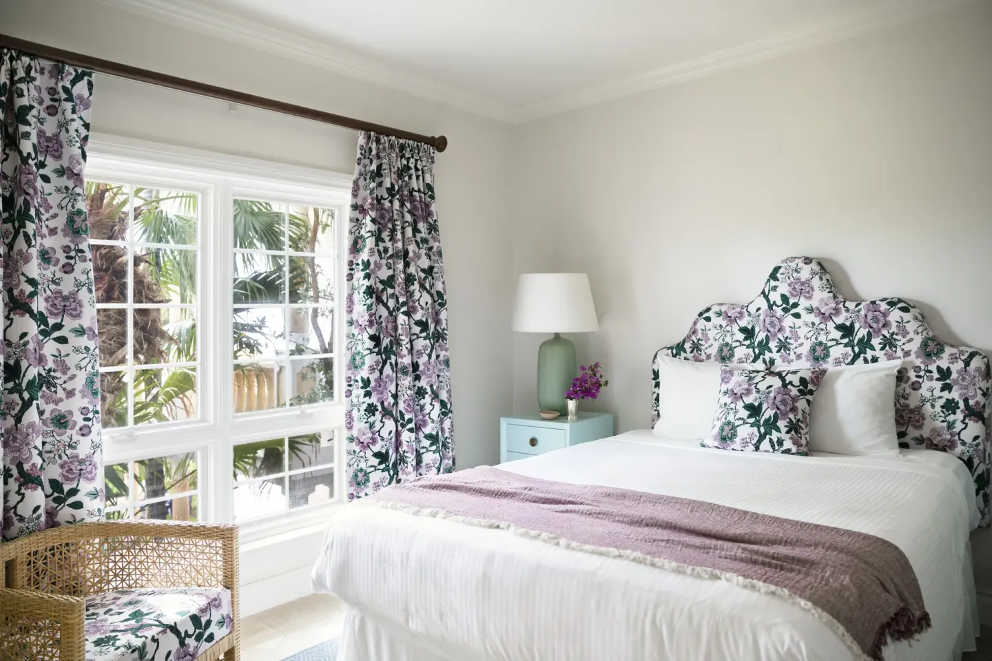 Guest room with a bed, floral headboard, and palm-framed window at Point Grace.