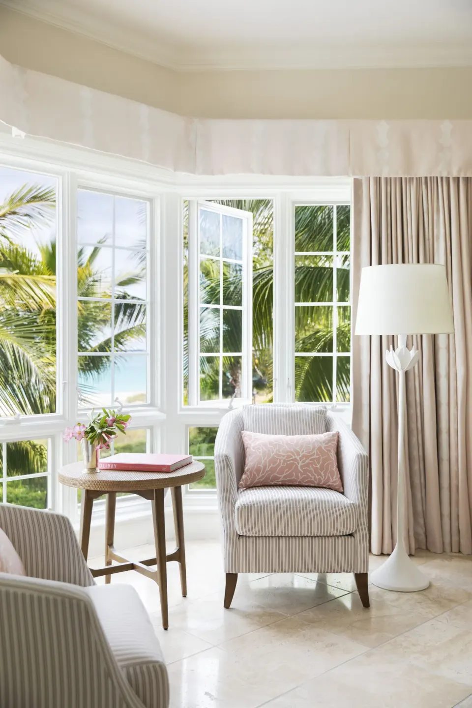 Sitting area with striped armchairs and open windows at Point Grace.