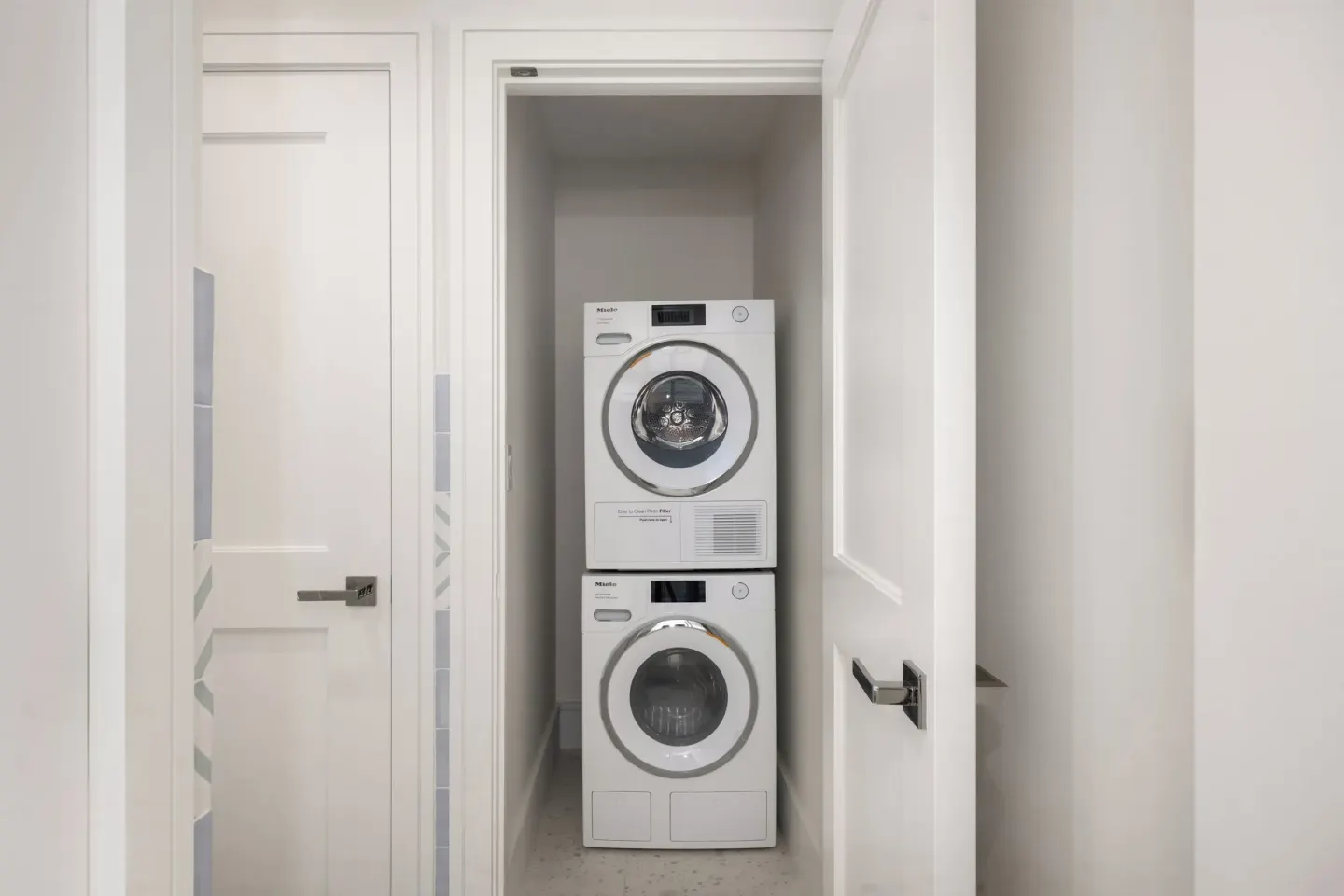 Stacked laundry machines in a guest suite closet at Point Grace.