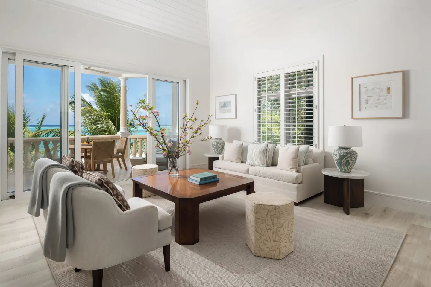 Bright ocean-view living room with sofas and balcony at Point Grace.