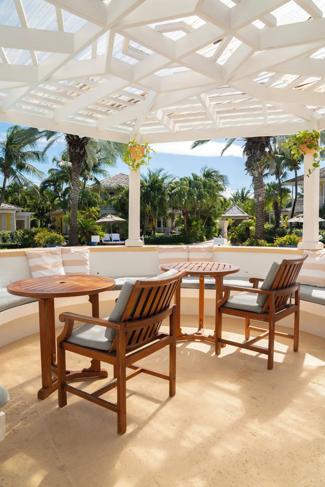 Open-air lounge with wood tables, chairs, and garden views at Point Grace.