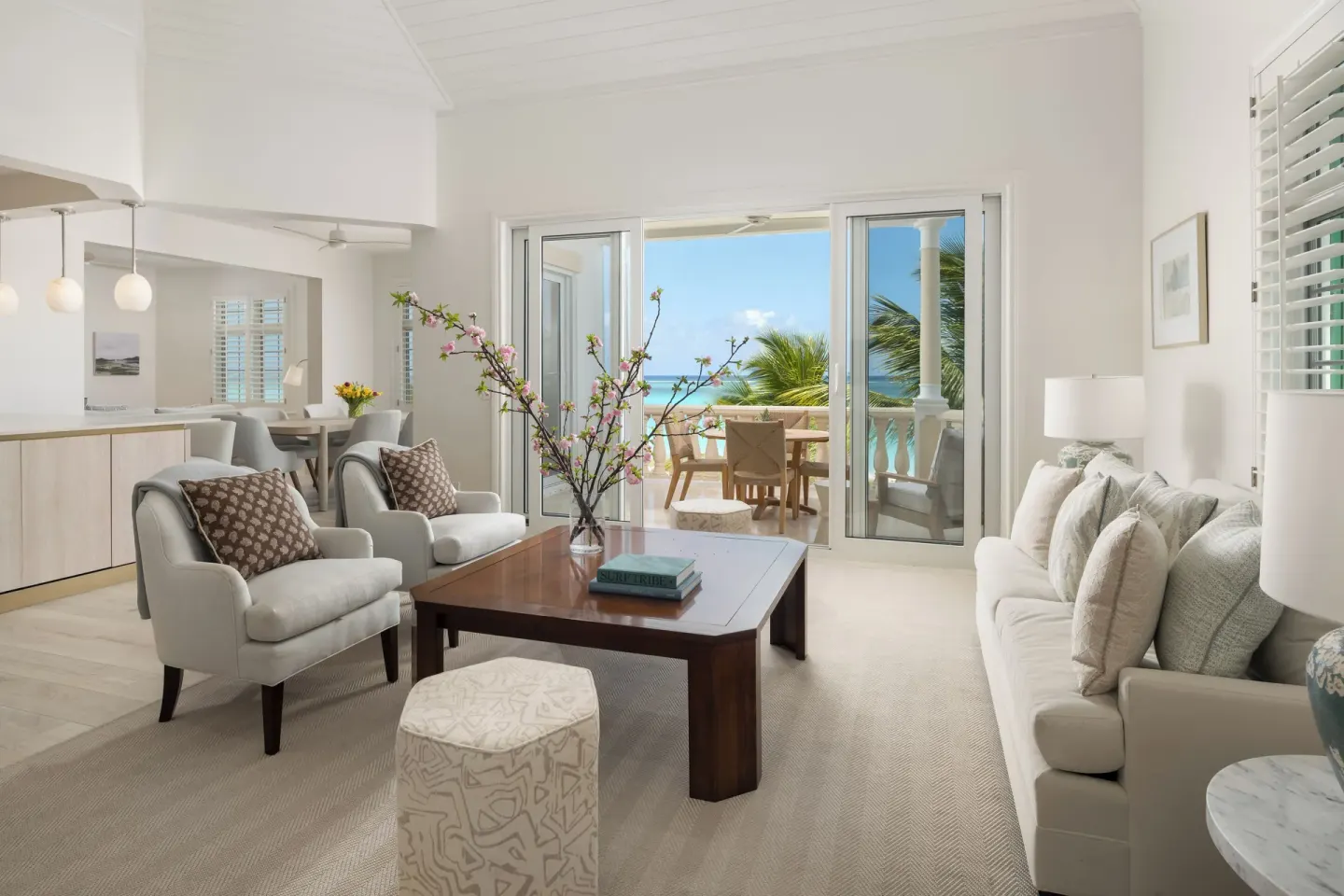 Open living and dining area with balcony doors facing the ocean at Point Grace.