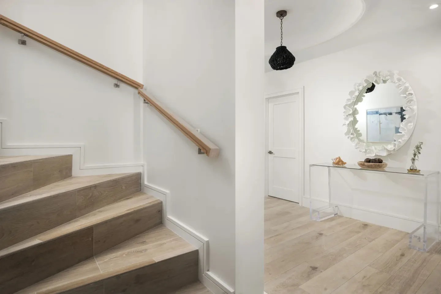 White stair hall with wood steps and a decorative mirror at Point Grace.