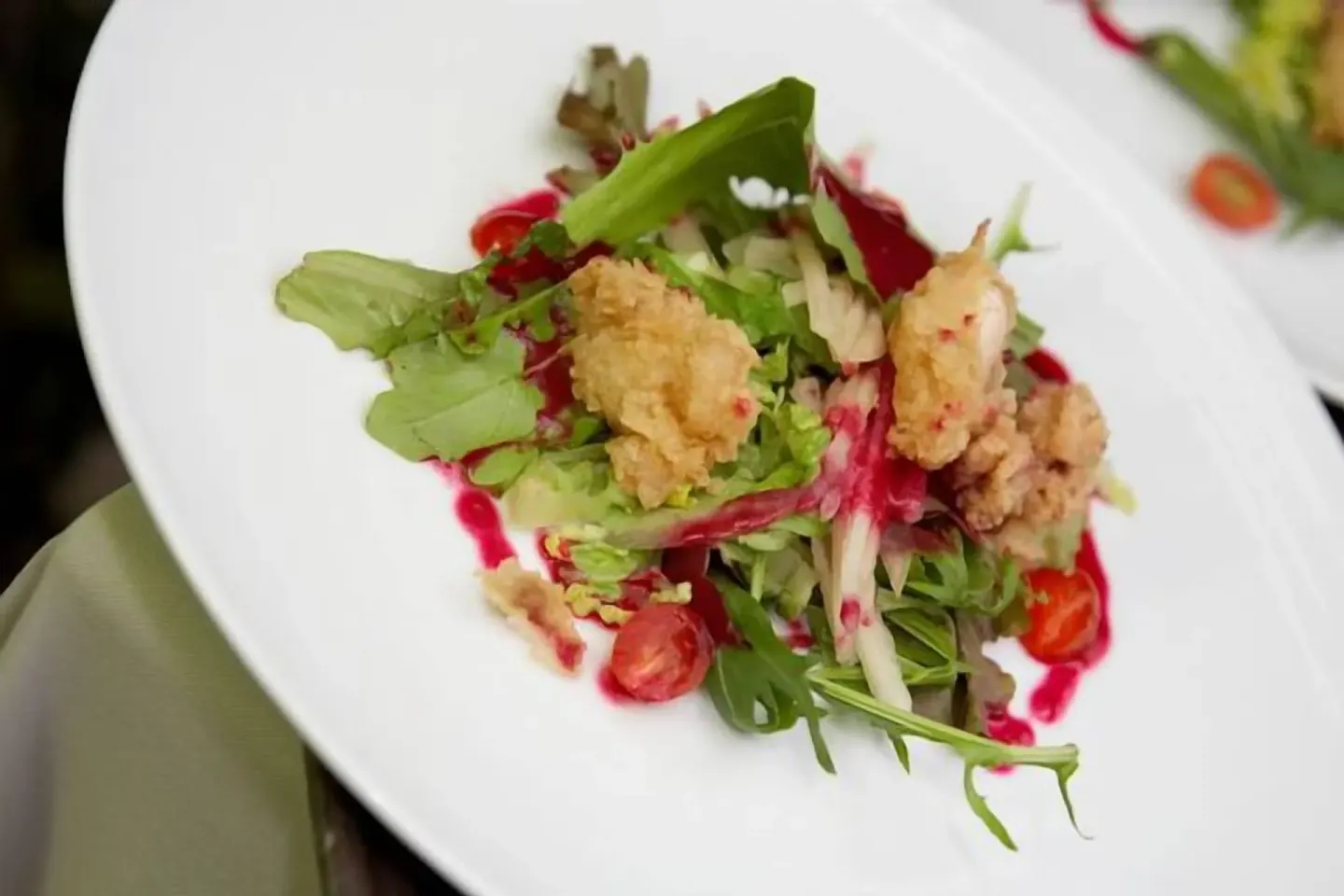 Plated salad with greens, tomatoes, fried pieces, and red sauce at Point Grace.
