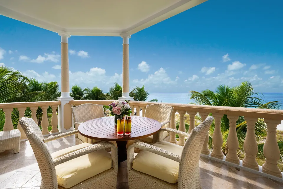 Oceanfront suite balcony with wicker seating and sea view at Point Grace.