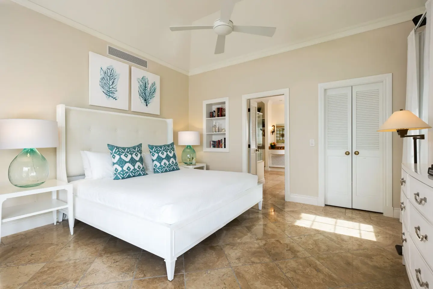 King bedroom with white bed and open bathroom doorway at Point Grace.