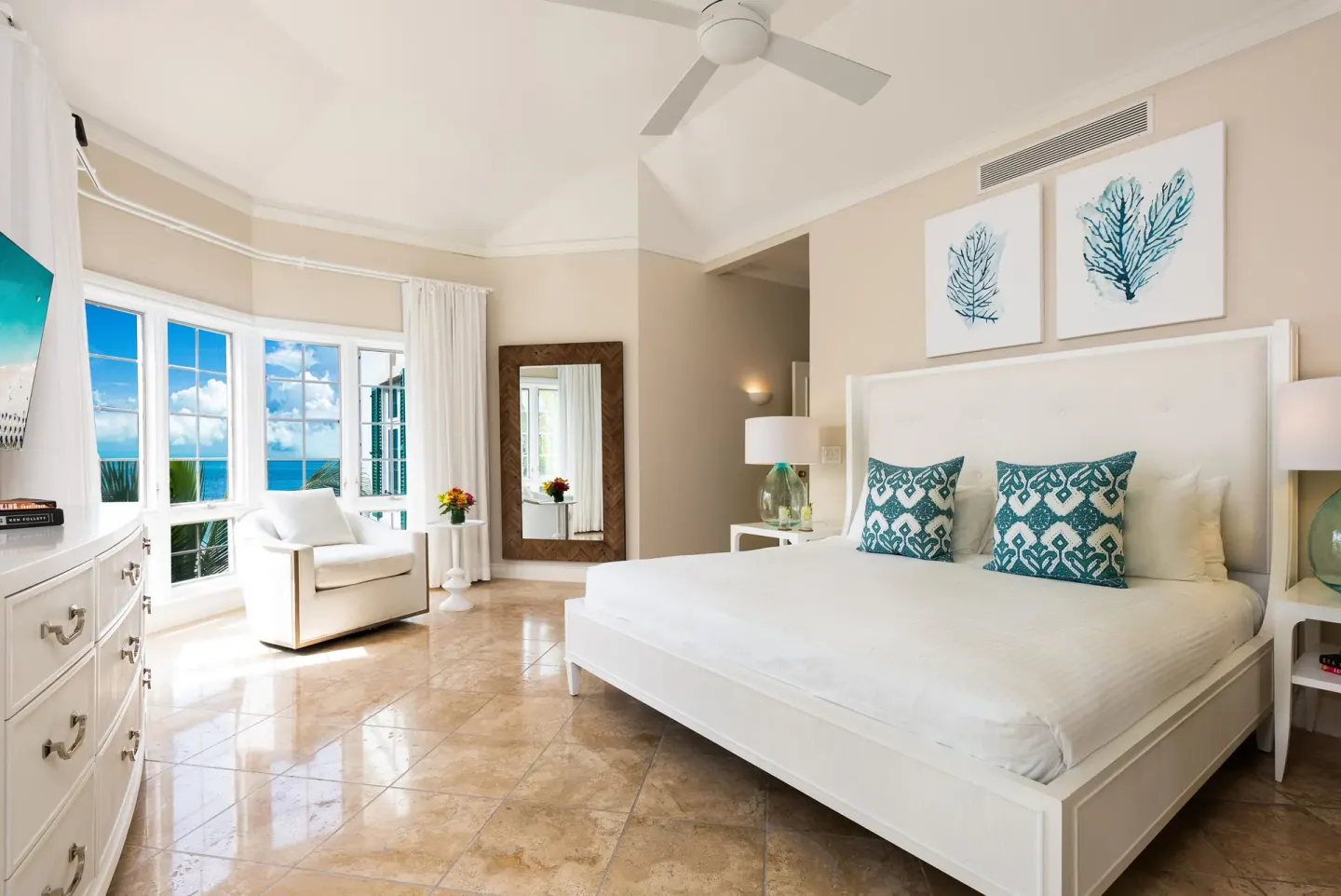 King bedroom with ocean-facing windows and lounge chair at Point Grace.