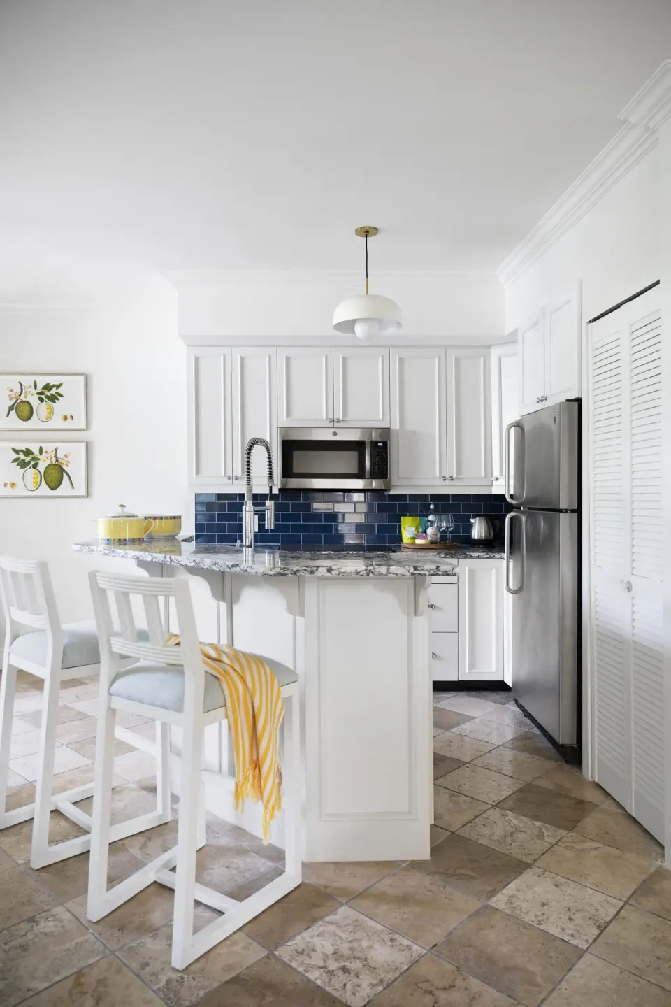 Suite kitchen with white cabinets, bar stools, and blue tile backsplash at Point Grace.