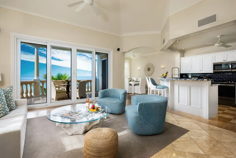Oceanfront suite living area with kitchen and balcony doors at Point Grace.