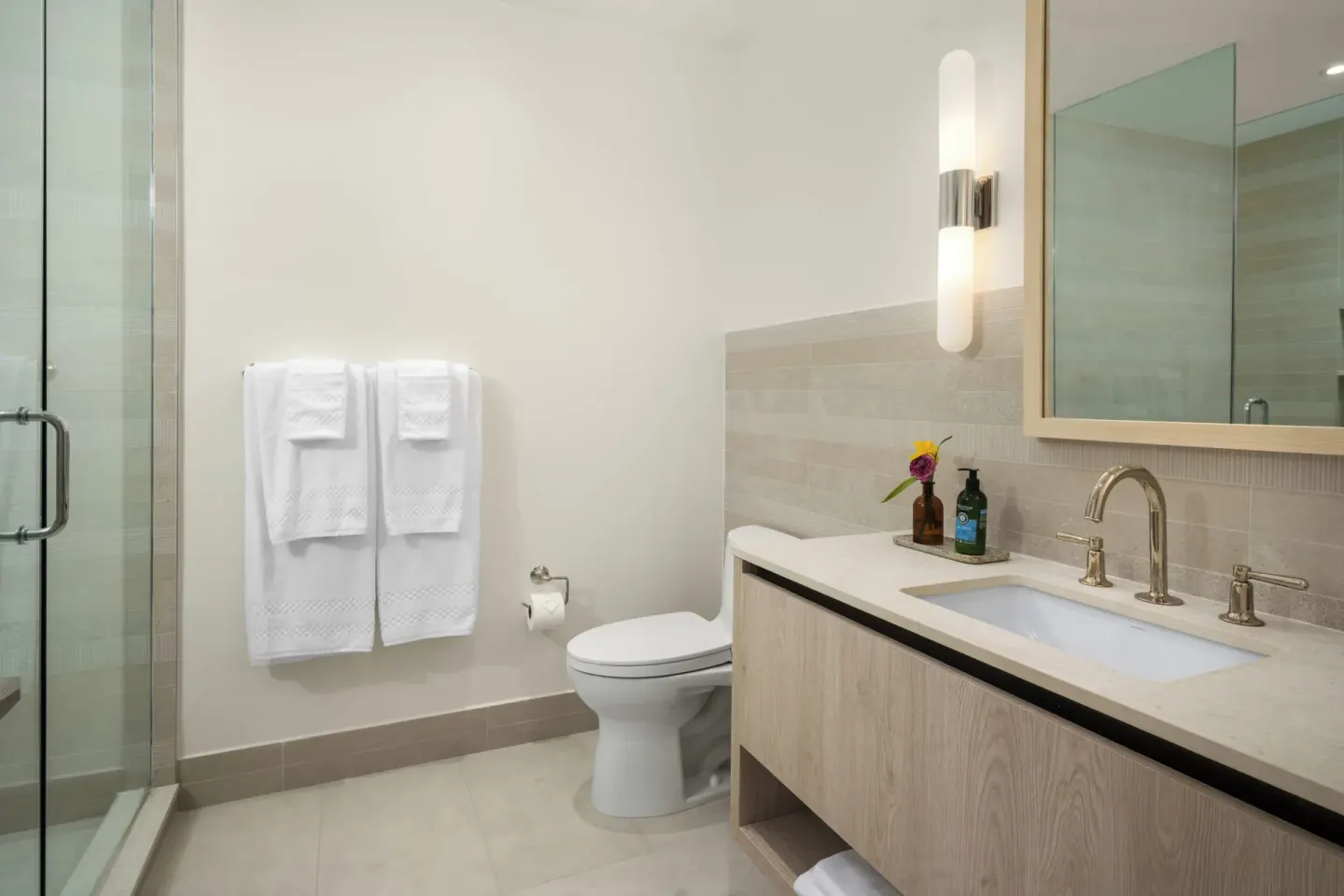 Oceanfront two-bedroom luxury suite bathroom at Point Grace with vanity, shower, towels, and toilet.