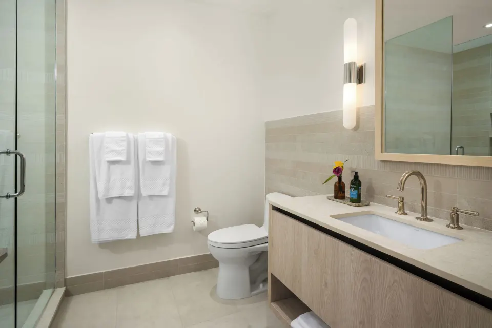 Oceanfront two-bedroom luxury suite bathroom at Point Grace with vanity, shower, towels, and toilet.