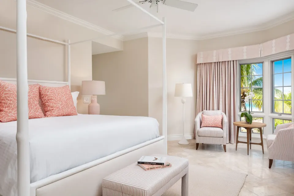 Oceanfront two-bedroom luxury suite bedroom at Point Grace with four-poster bed and sea-facing windows.