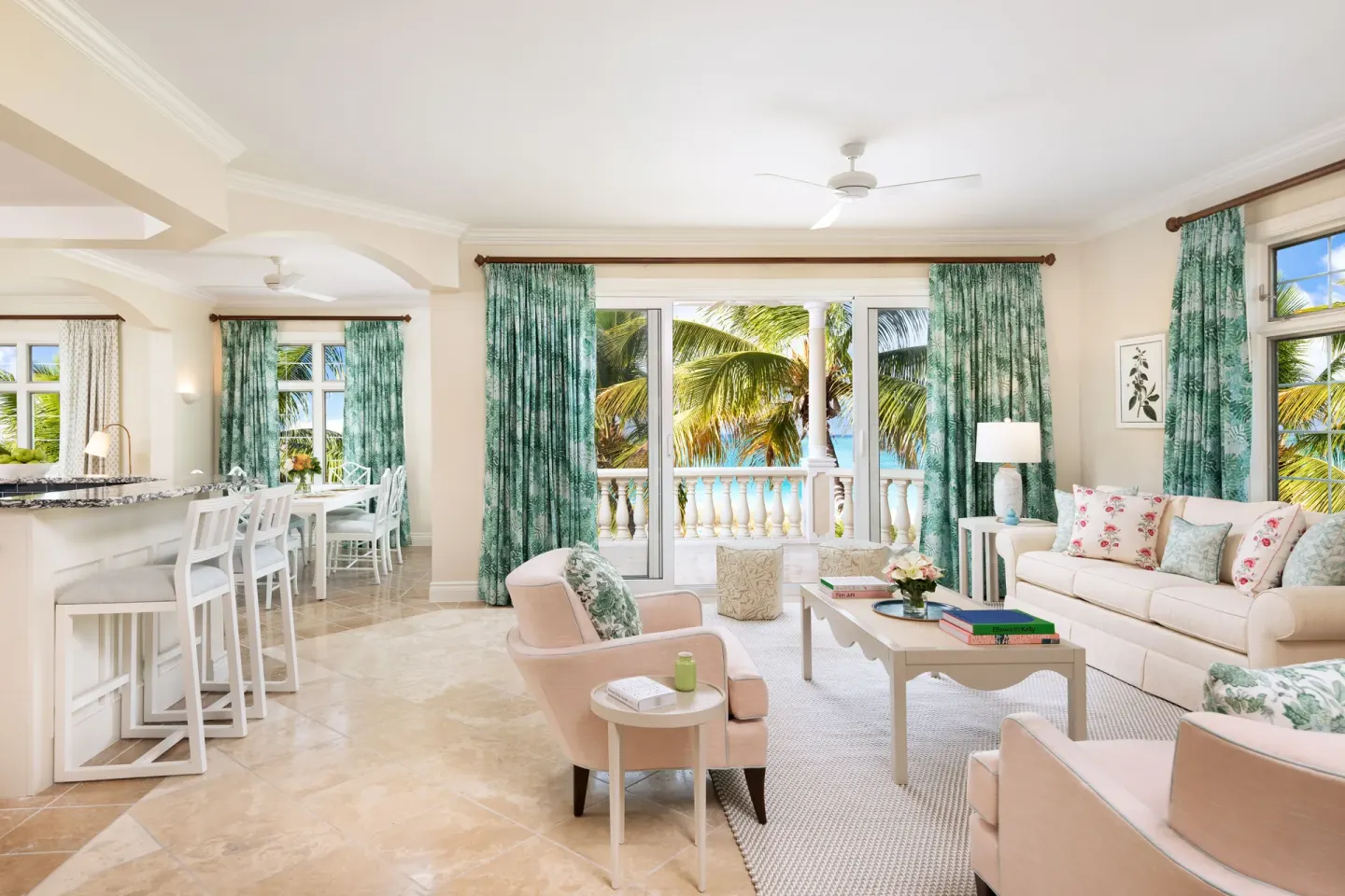 Oceanfront two-bedroom luxury suite living and dining area at Point Grace with balcony and palms.