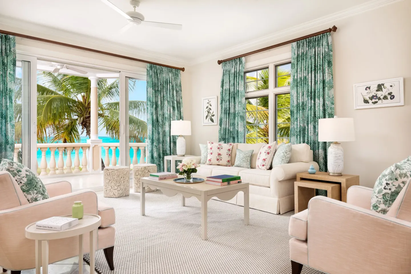Oceanfront two-bedroom luxury suite sitting area at Point Grace with sofa, armchairs, and balcony view.