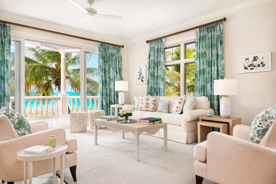 Oceanfront two-bedroom luxury suite sitting area at Point Grace with sofa, armchairs, and balcony view.