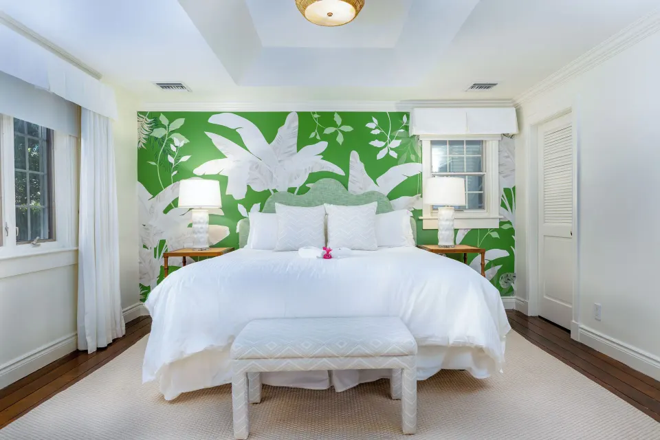 White bed with green floral mural in a Pool View Cottage 1 Bedroom Suite at Point Grace.