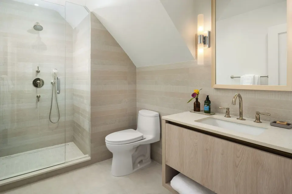 Oceanfront one-bedroom suite bathroom with shower, toilet, and vanity at Point Grace.
