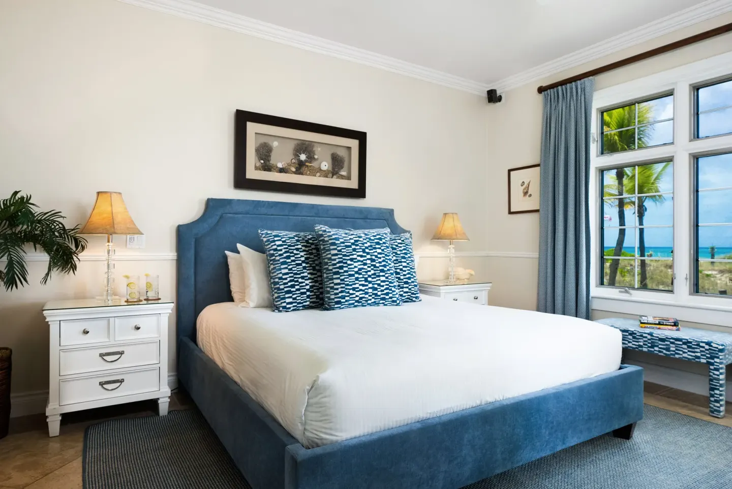 Oceanfront one-bedroom suite bedroom with blue bed and sea view at Point Grace.