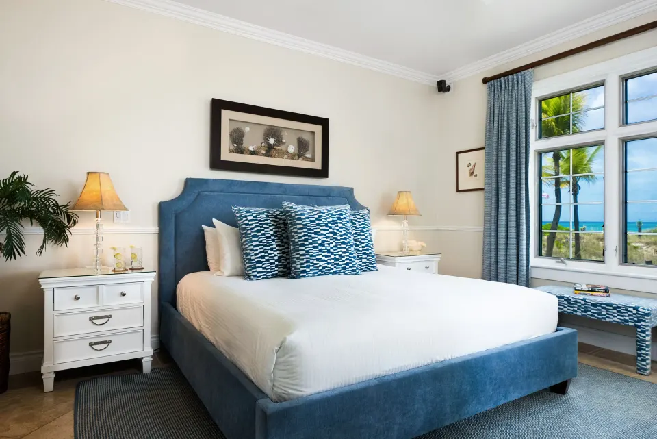 Oceanfront one-bedroom suite bedroom with blue bed and sea view at Point Grace.