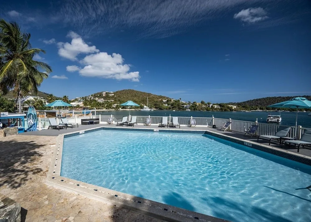 Pool beside the bay with loungers and blue umbrellas at Point Pleasant Resort.