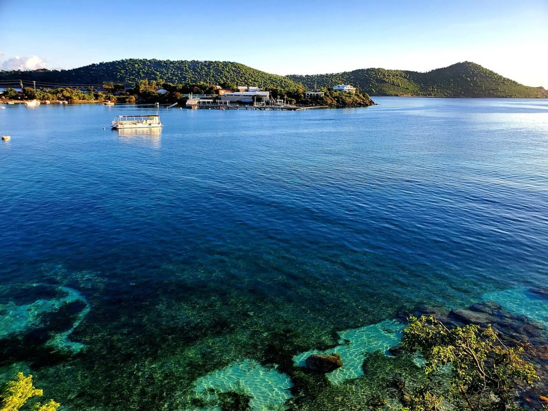 Clear blue water, a small boat, and green hills are visible from Point Pleasant Resort.