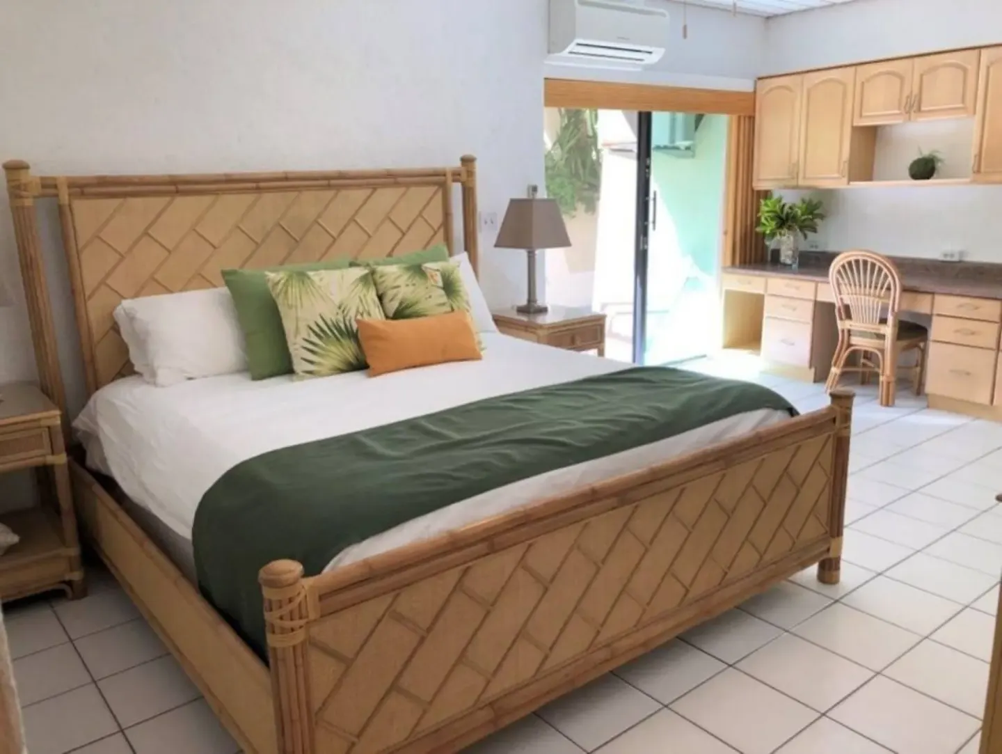 Guest room with bamboo-style bed, kitchenette, desk, and patio door at Point Pleasant Resort.