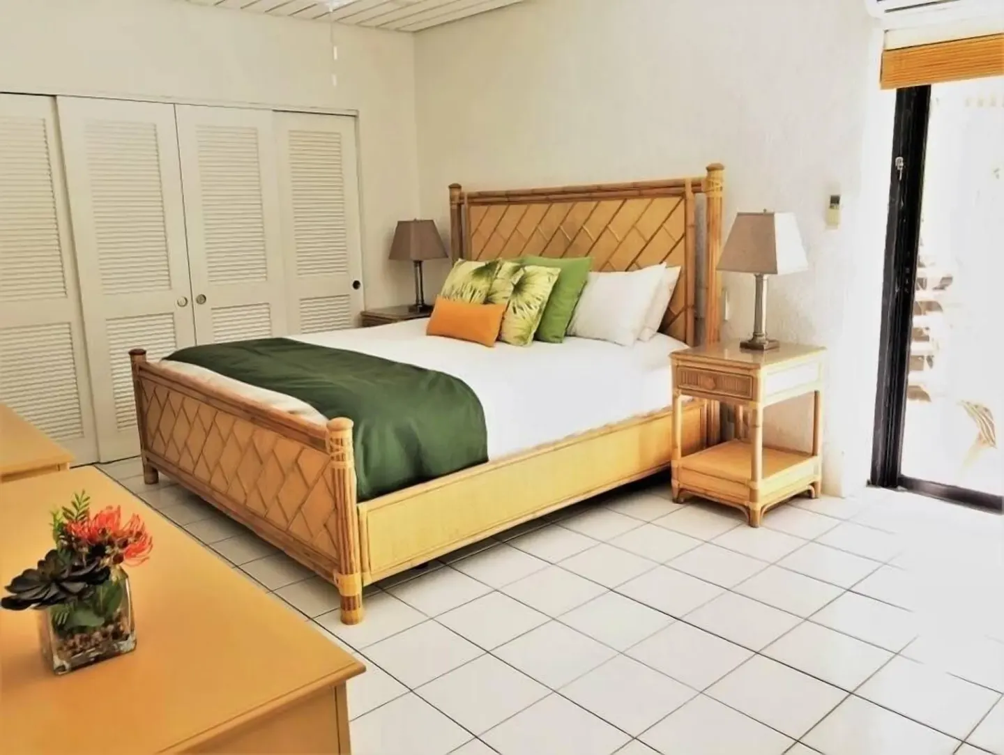 Guest room with bamboo-style bed, nightstands, closet doors, and patio light at Point Pleasant Resort.