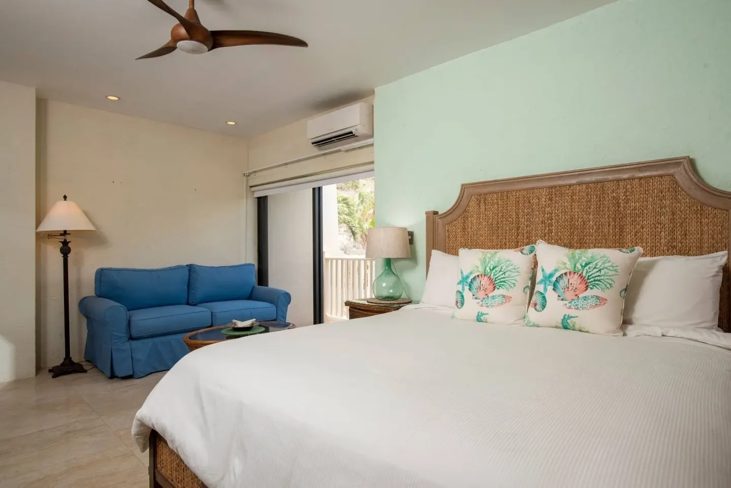 Guest room with a bed, blue sofa, and sliding glass door at Point Pleasant Resort.