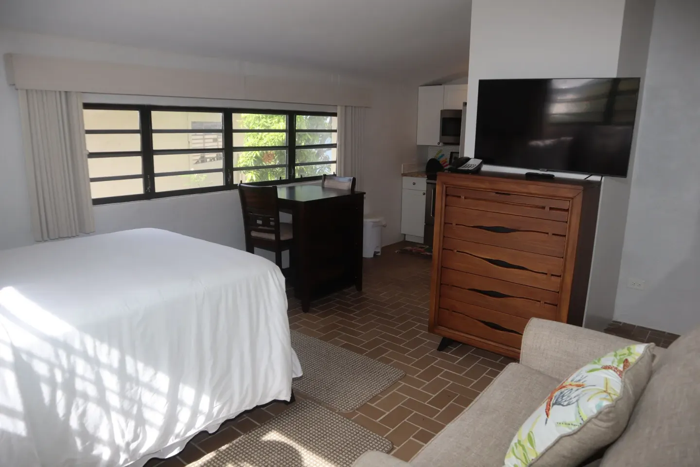 Guest room with bed, desk, dresser, TV, and sofa at Point Pleasant Resort.