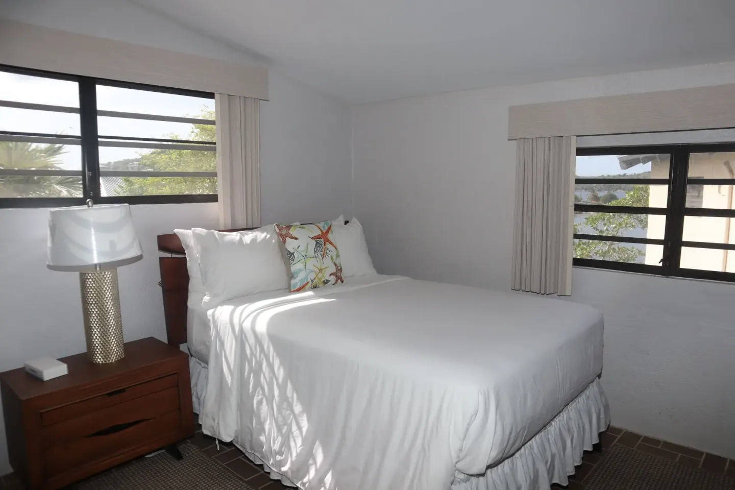Guest room bed between two louvered windows at Point Pleasant Resort.