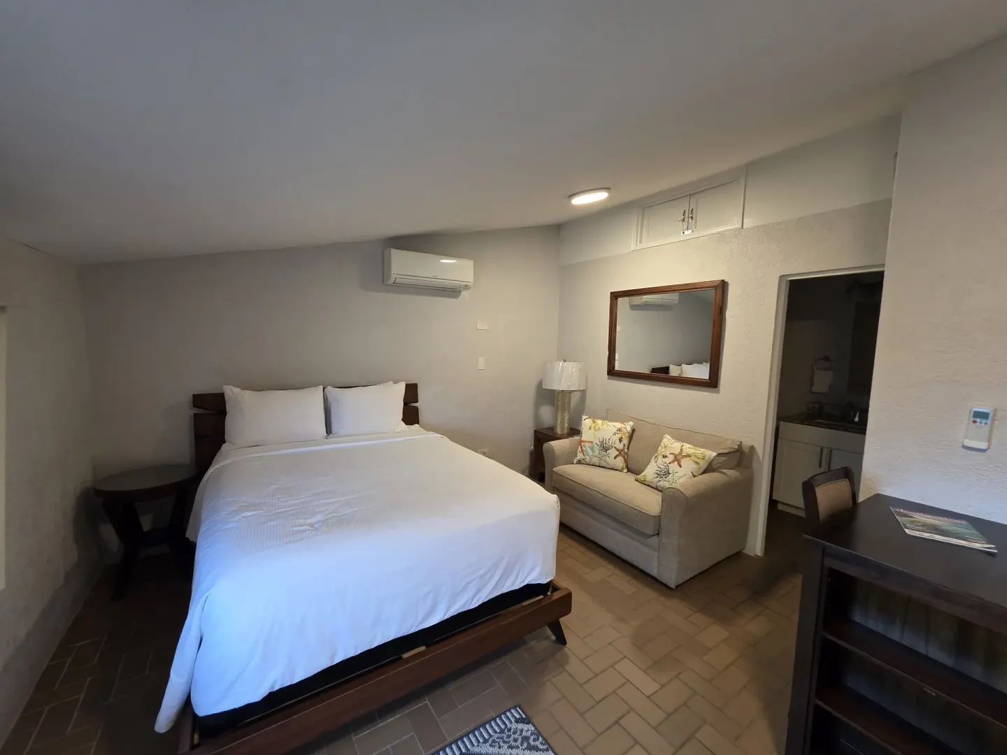 Guest room with bed, sofa, desk, mirror, and open vanity area at Point Pleasant Resort.