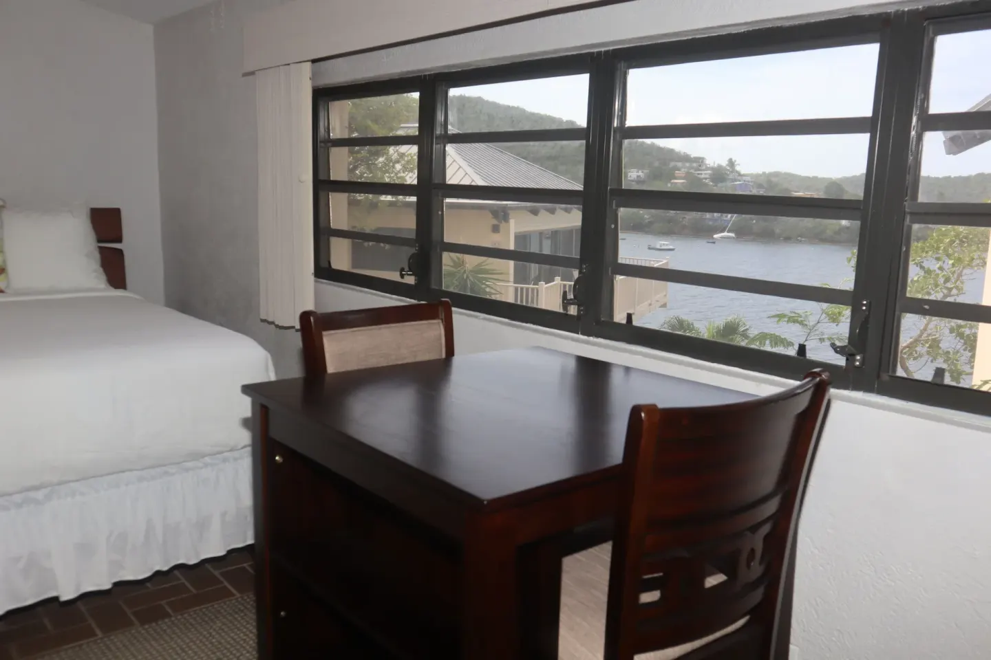 Guest room desk and bed beside windows with water views at Point Pleasant Resort.