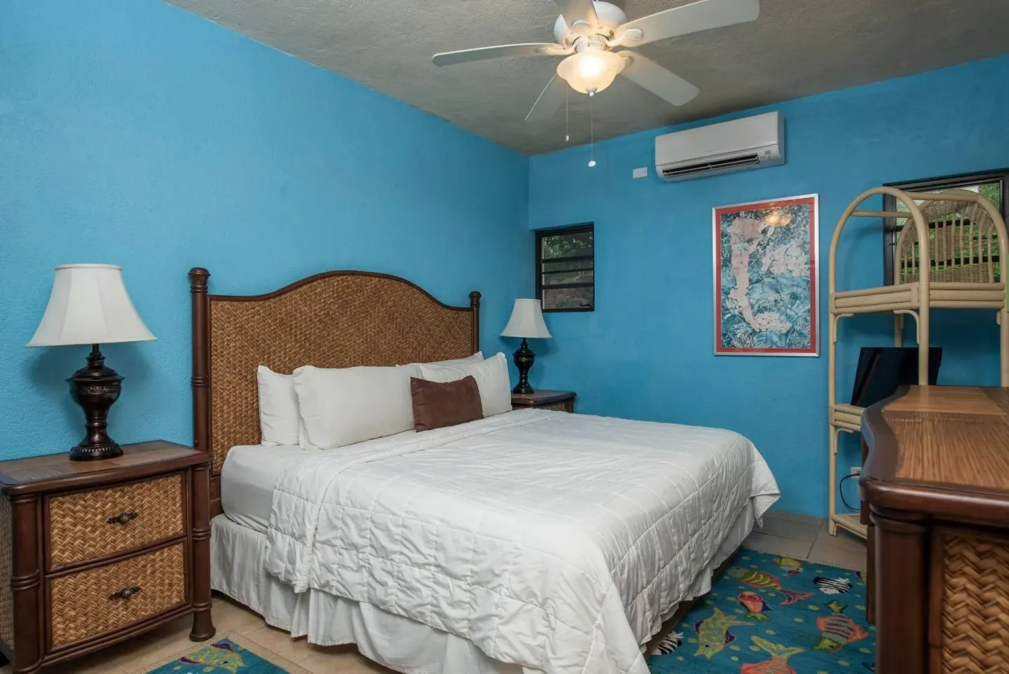Guest room with king bed, blue walls and wicker accents at Point Pleasant Resort.