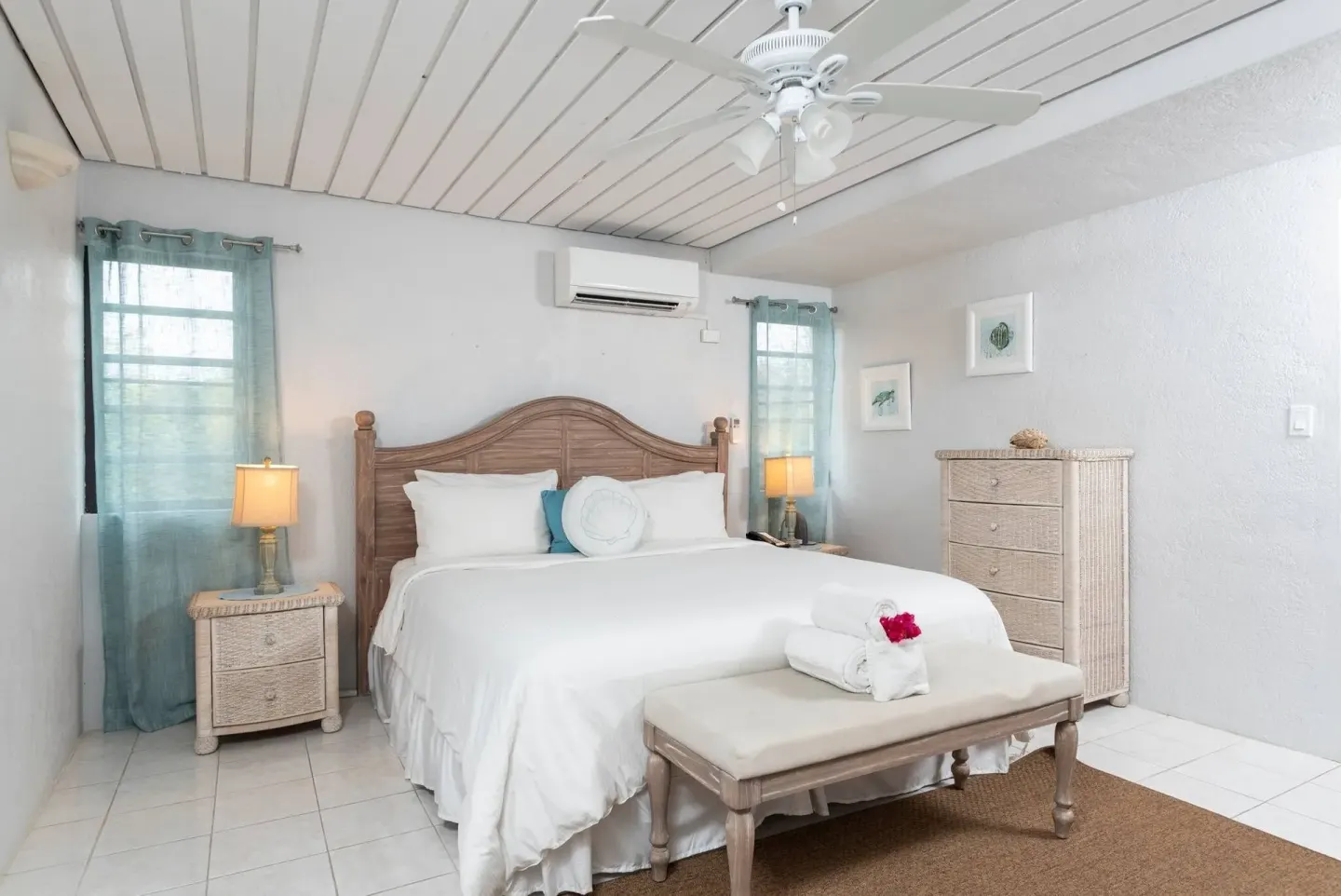 Guest room with king bed, bench and white wicker furniture at Point Pleasant Resort.